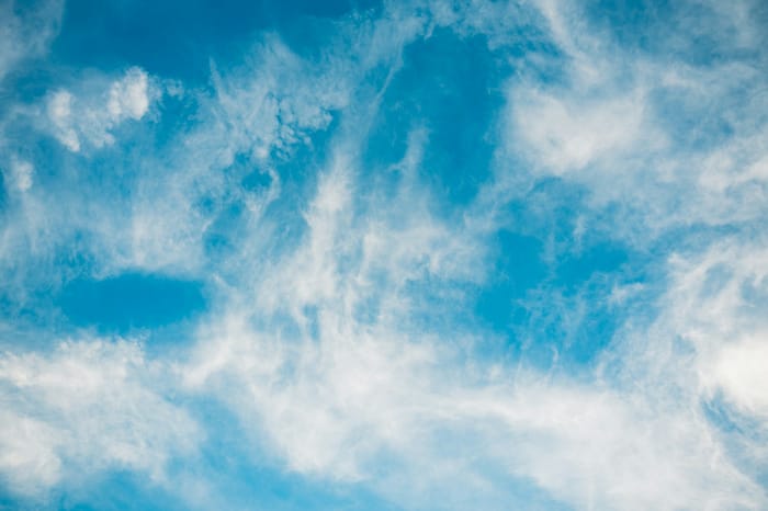 Wispy white clouds drifting across a bright blue sky